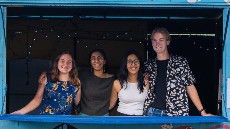 Four students hugging and posing to the camera inside a small container